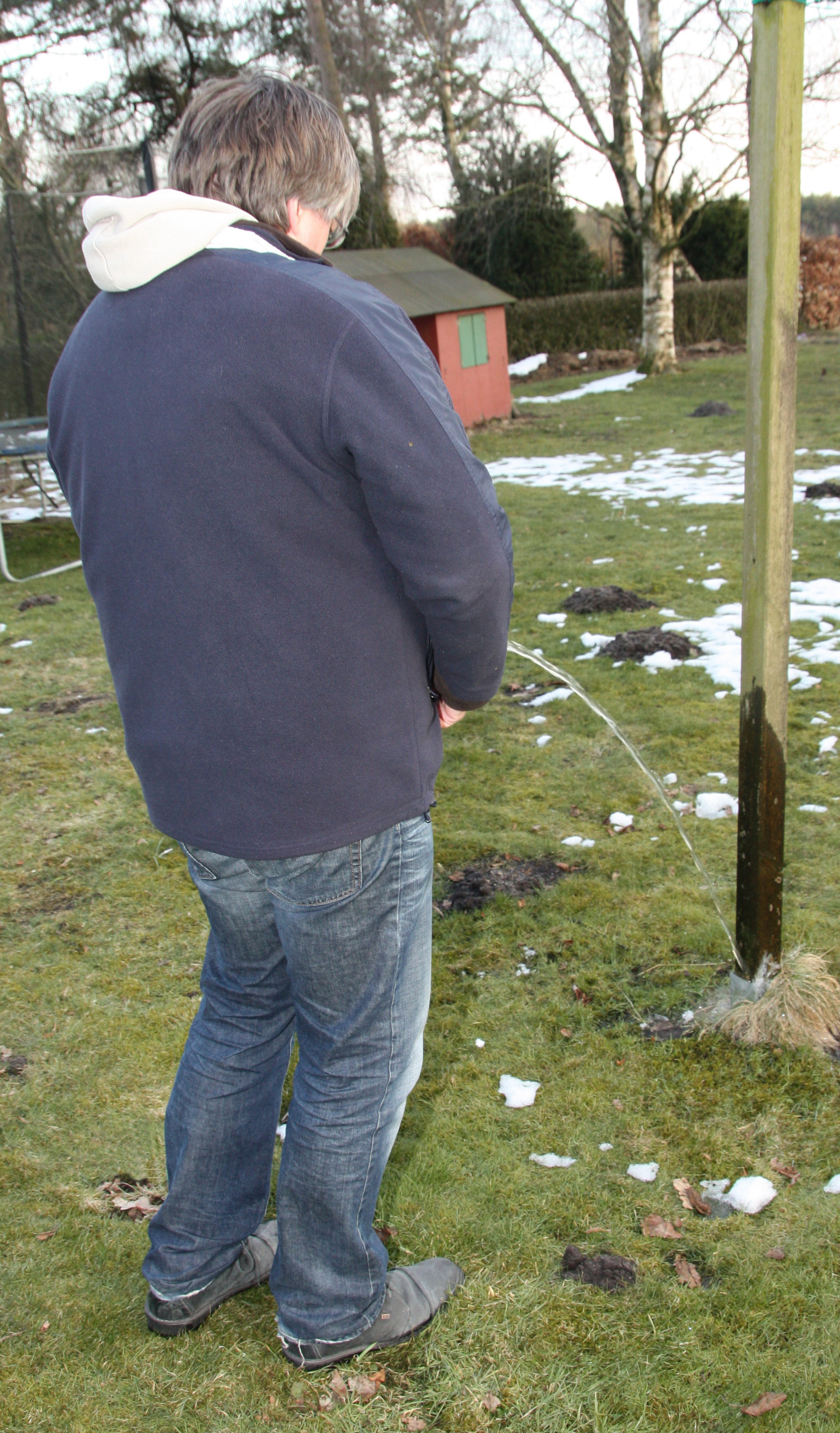 Eine nachgestellte Szene: Ein fremder Mann pinkelt an den Wäschepfahl