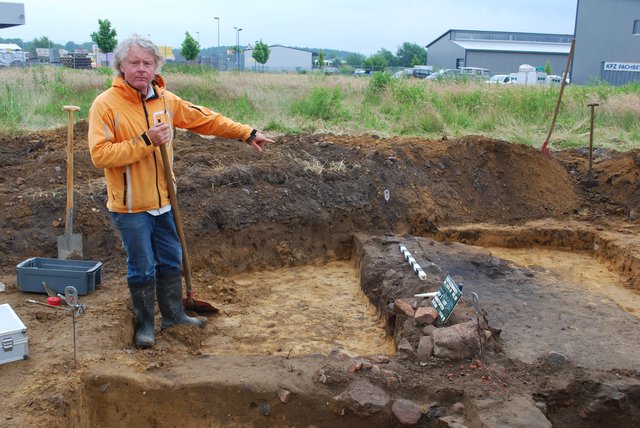 Willi Müller, Grabungstechniker des Helms-Museums, zeigt die Fundstelle eines Siedegefäßes