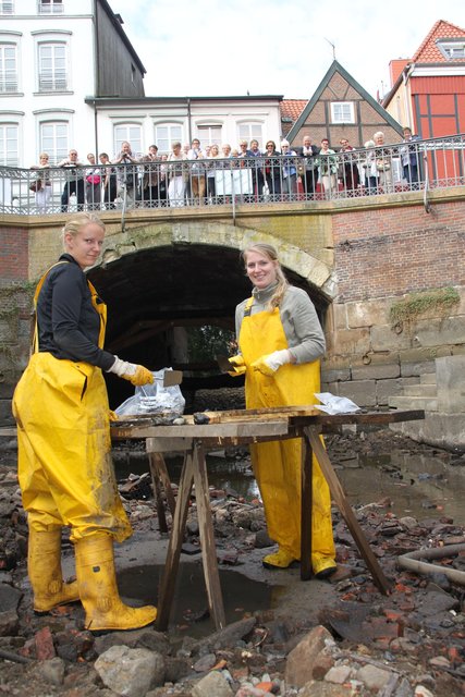Myga Jalowczarz (li.) und Wenthe Krüger schürfen im modrigen Hafenbecken nach "Schätzen im Schlick", Touristen beobachten das Spektakel von der Hudebrücke