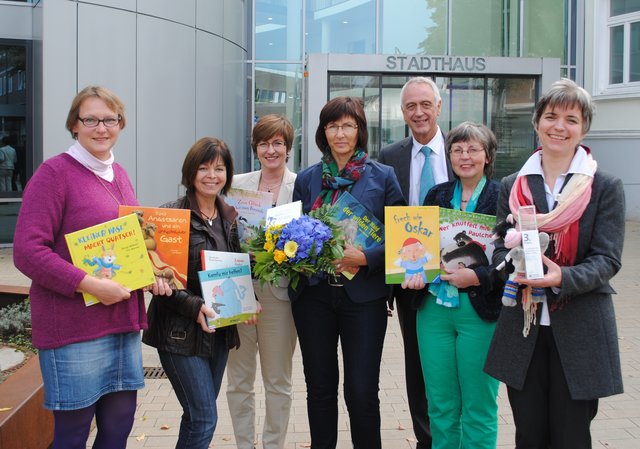 Was für ein Erfolg! Stadtbibliotheks-Leiterin Ulrike Mensching (re.) und ihr Team der Rucksackbibliothek (v.li.) Stefanie Blanken, Ute Soodmann, Heike Bretschneider und Erika Wierschem präsentieren den Preis vor dem Stadthaus. Bürgermeister Jürgen Badur und Katja Oldenburg-Schmidt, Erste Stadträtin, gratulieren