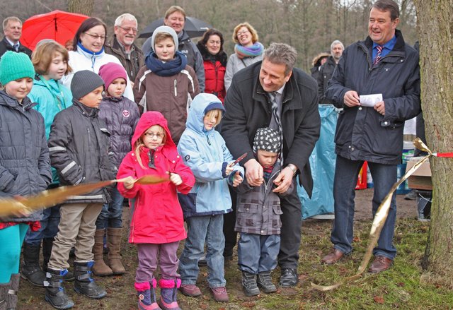 Gemeindirektor Rainer Schlichtmann (re.) und Bürgermeister Michael Ospalski durchschneiden gemeindsam mit den Kindern das goldene Band