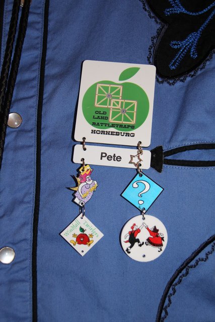 Auf dem "badge" steht der Name des Tänzers und der Club, dem er angehört. Die "dangles" sind Souvenirs anderer Vereine
