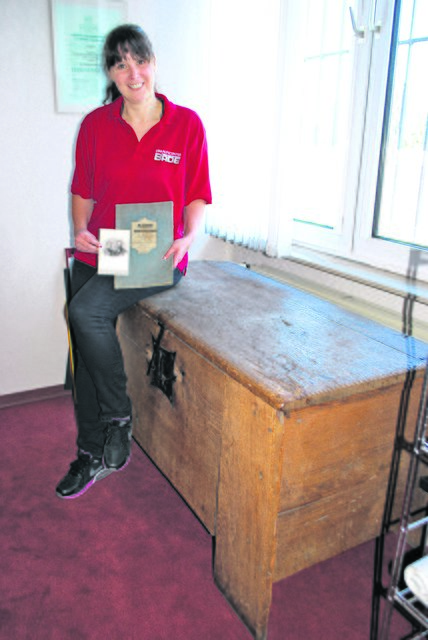 Alice Kurze mit einer Truhe aus den Anfängen des Kaufhauses Bade, dem Bild der Huths und einem Namensverzeichnis der Einwohner der Amtsvogtei Tostedt