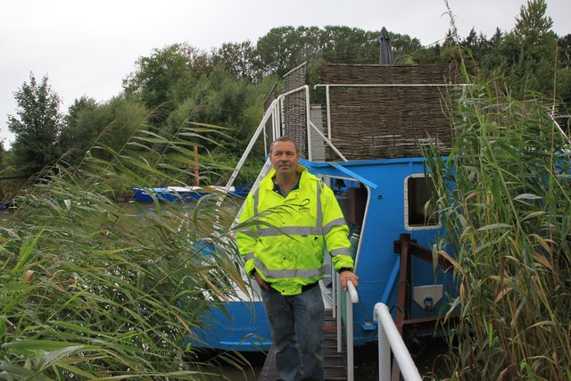 Jelle Makris vor einem seiner eigenhändig zu Hausboot-Hotels umgebauten Arbeitsschiffe im Gauensieker Hafen