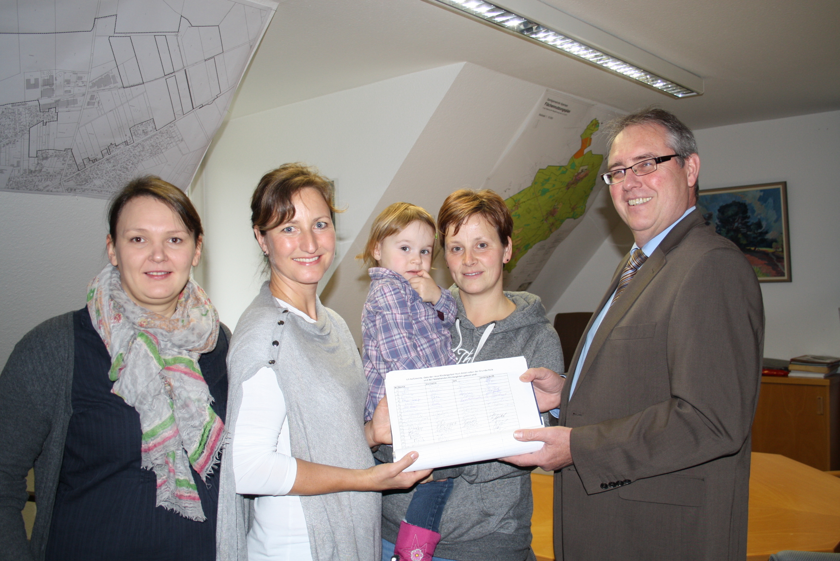 Helene Hesse, Tanja van der Vorst, Ina Dammann mit Tochter Henrike (2) überreichen Peter Sommer die Mappe mit den Unterschriften