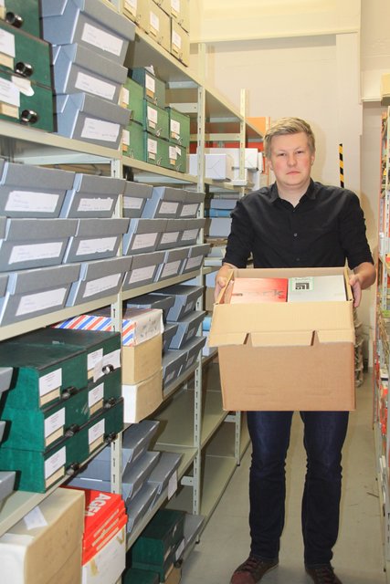 Archiv-Mitarbeiter Sven Müller mit einem Teil der Rihsé-Fotosammlung, die Kartons und mehrere Aktenmeter füllt