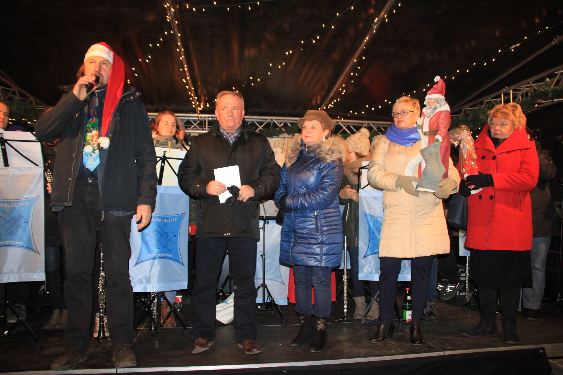 Markteröffnung auf der Show-Bühne: Himmelpfortens Bürgermeister Bernd Reimers (li.) mit seinem Amtskollegen aus der polnischen Partnergemeinde Puck, Tadeucz Puszkarcuzk. Polnische Lehrerinnen (re.) überreichten zwei Weihnachtsmann-Figuren