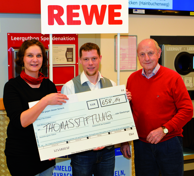 Jutta Sepe (li.) und Hans Hermann-Meyer von der Thomasstiftung bei der Scheckübergabe mit Rewe-Marktleiter Kristof Burmeister