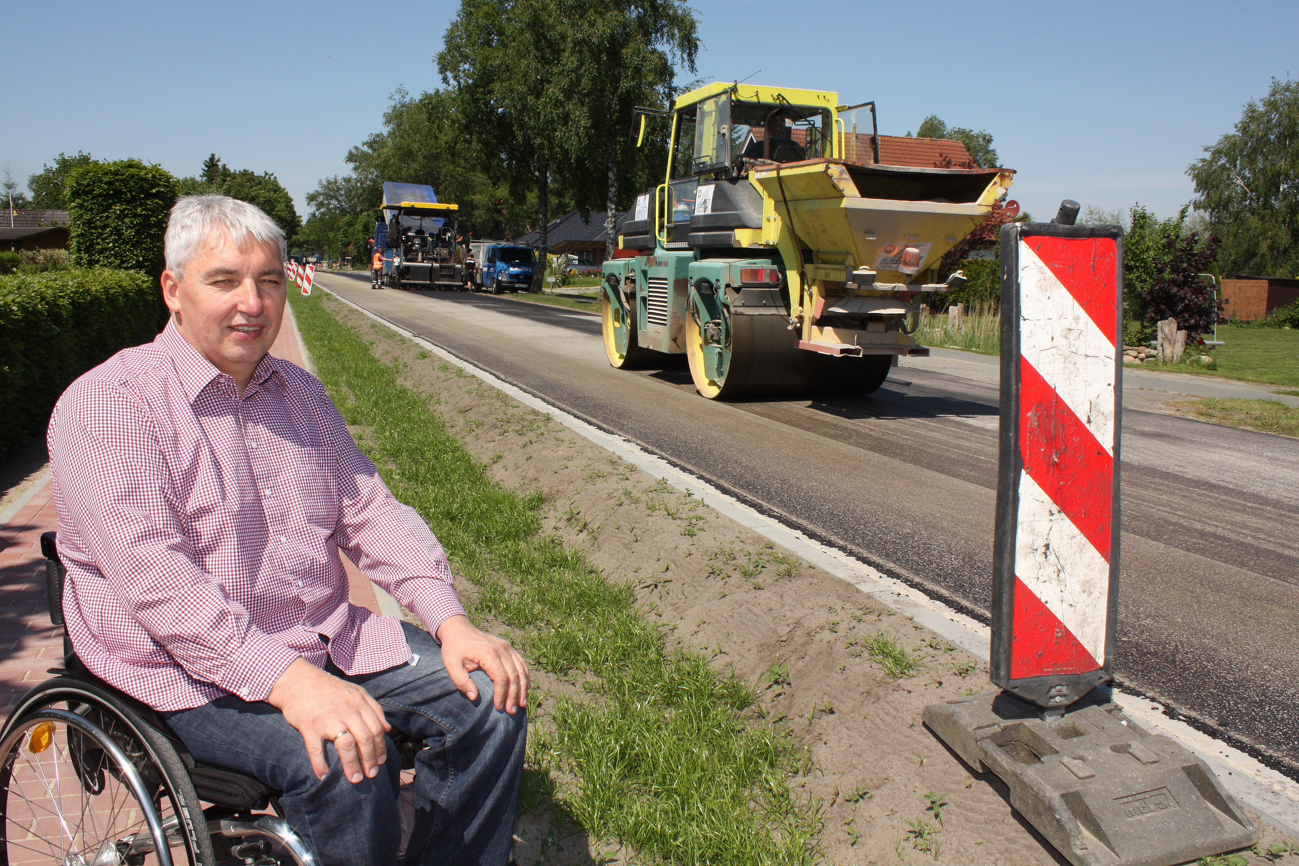 Bürgermeister Uwe Arndt freut: Die Bauarbeiter tragen den obersten Straßenbelag auf. Danach ist alles fertig