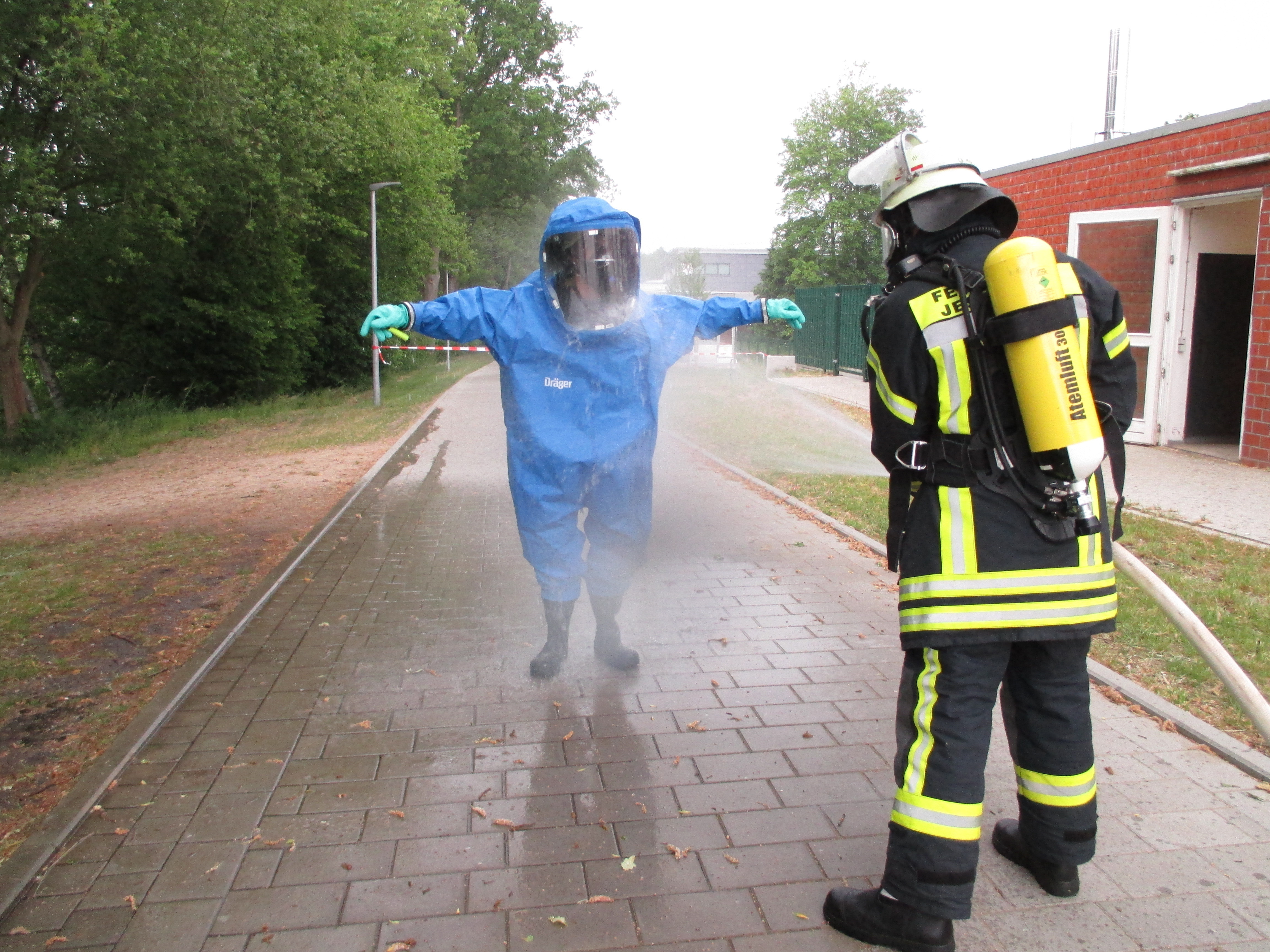 Nach getaner Arbeit unter Vollschutz wird der Feuerwehrmann von seinem Kollegen abgespritzt