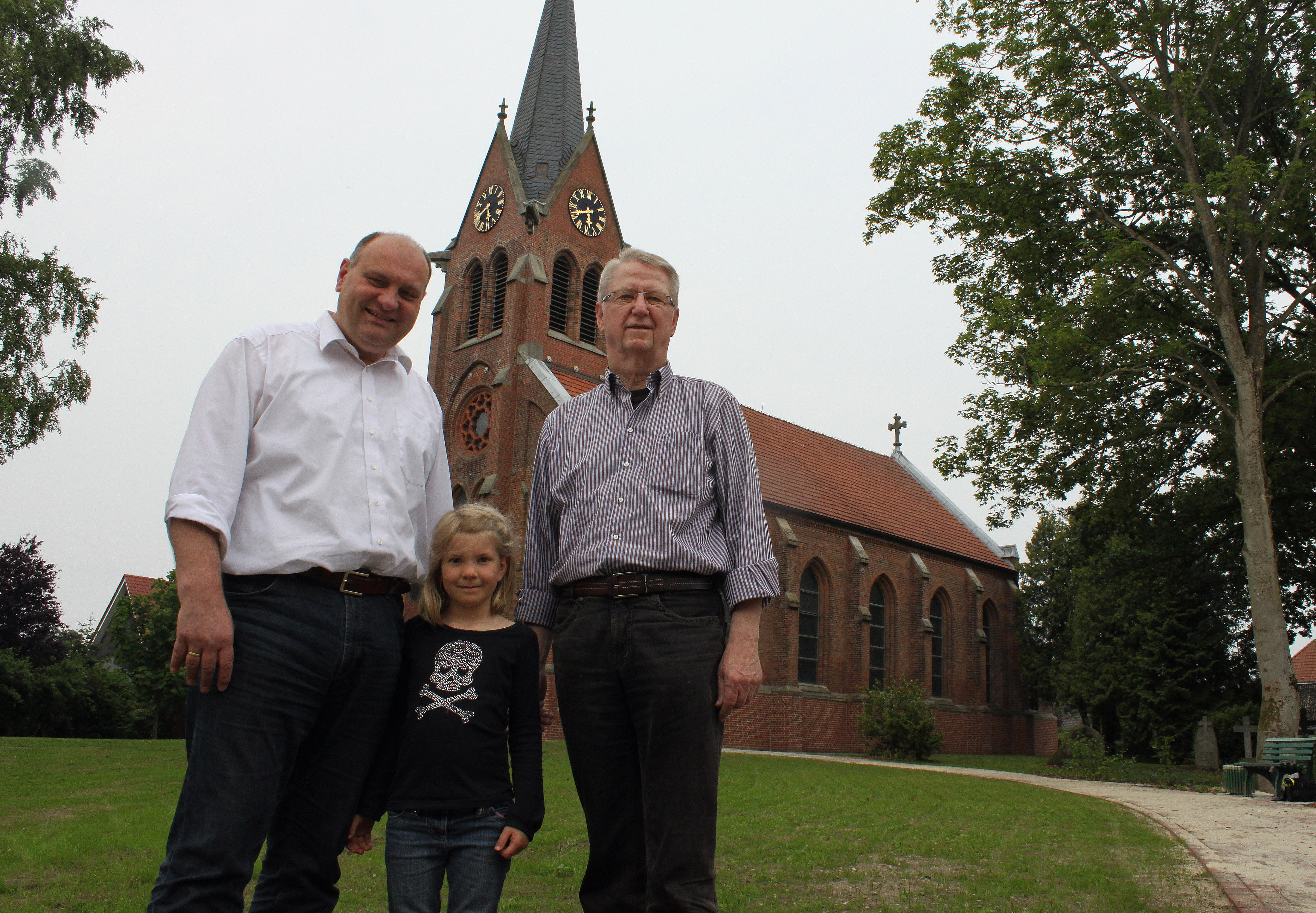 Freuen sich über den neuen Kirchplatz (v.li.): Pastor Detlef Beneke mit Tochter Paula und Hans-Hermann Raap vom Kirchenvorstand