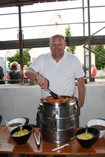 Lars Höft hält Würstchen und verschiedene Salate für die Gäste bereit