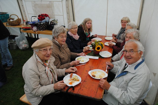 Zuflucht vor dem Regen: Diese Besucher ließen es sich im Zelt der Kirchengemeinde schmecken