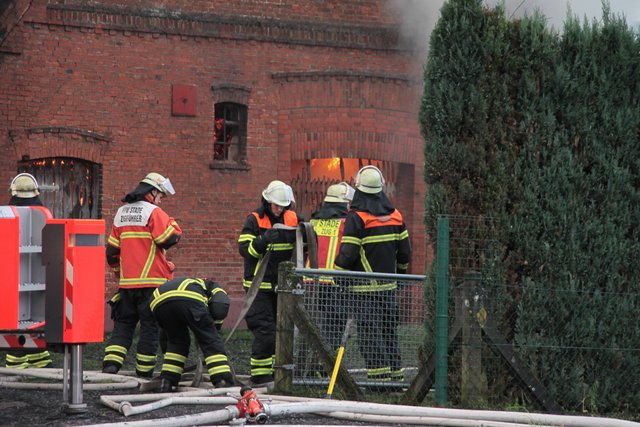 Hinter dem Backsteingiebel lodern helle Flammen