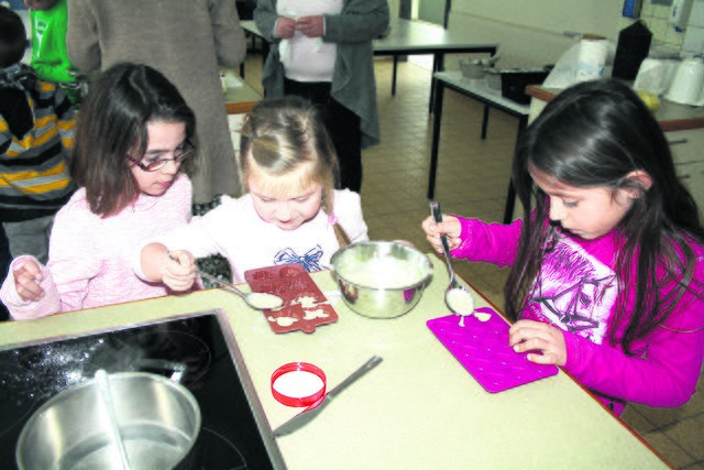 Dass bloß nichts daneben geht! Hochkonzentriert füllen die Kinder die Schokolade in kleine Pralinen-Förmchen