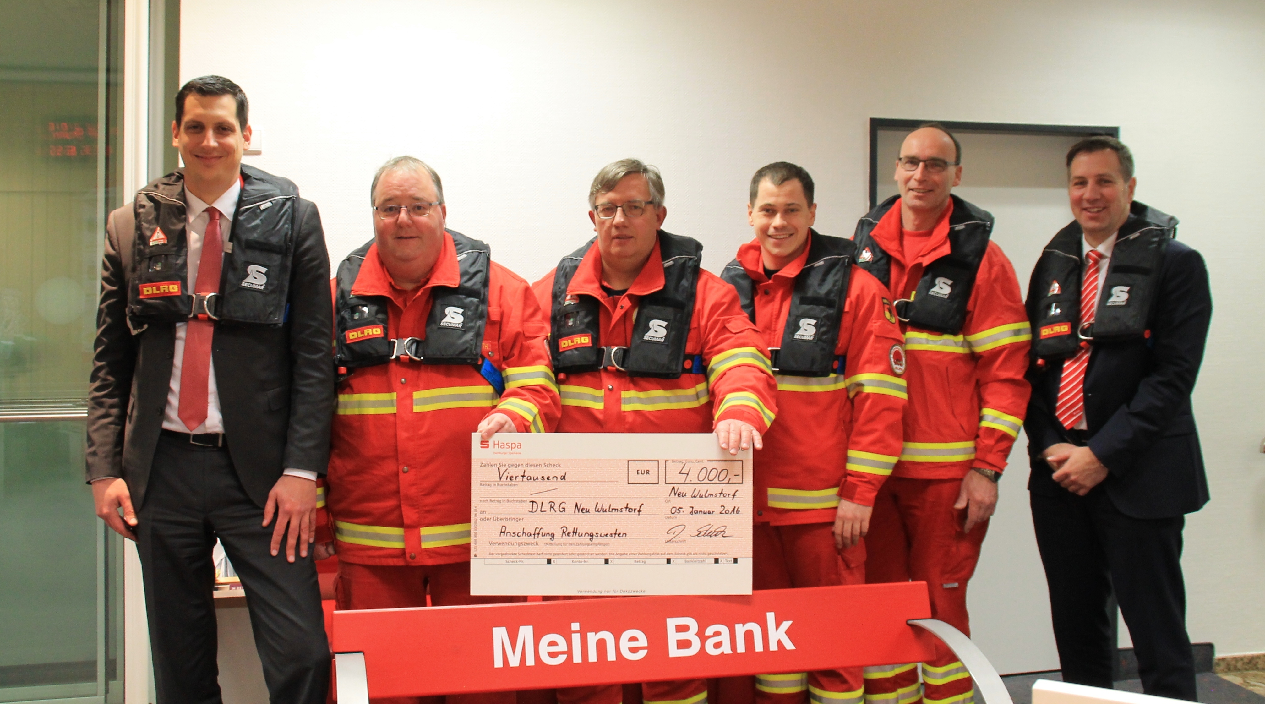 Eine gute Investition: Aktive der DLRG Neu Wulmstorf mit Haspa-Regionalleiter Kai Köster (li.) und Filialleiter Daniel Schulz (re.) die neuen Rettumgswesten