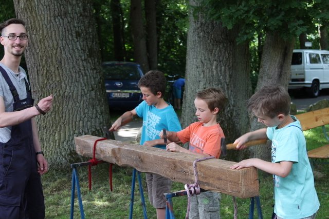 Mit großer Konzentration treiben diese Jungs während des Dorffests Nägel in einen Balken
