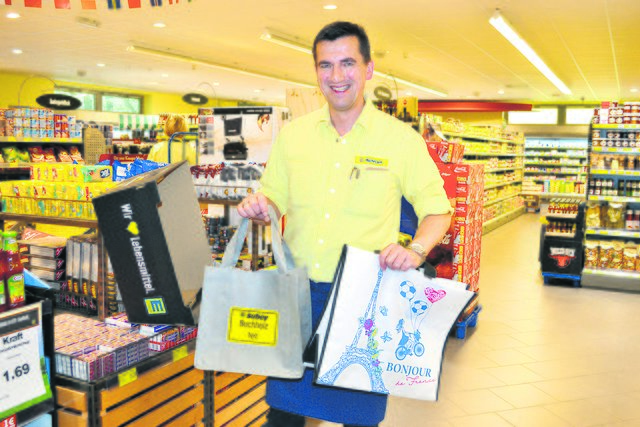Edeka-Subey-Marktleiter Oliver Michelsen mit Permanent-Tragetasche und „Repet-Bag“ neben den beliebten Einkaufskartons