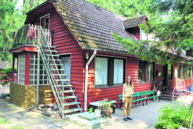 Mit diesem Gebäude fing alles an: Geschäftsführerin Bea Trampenau vor dem 1923 erbauten Holzhaus