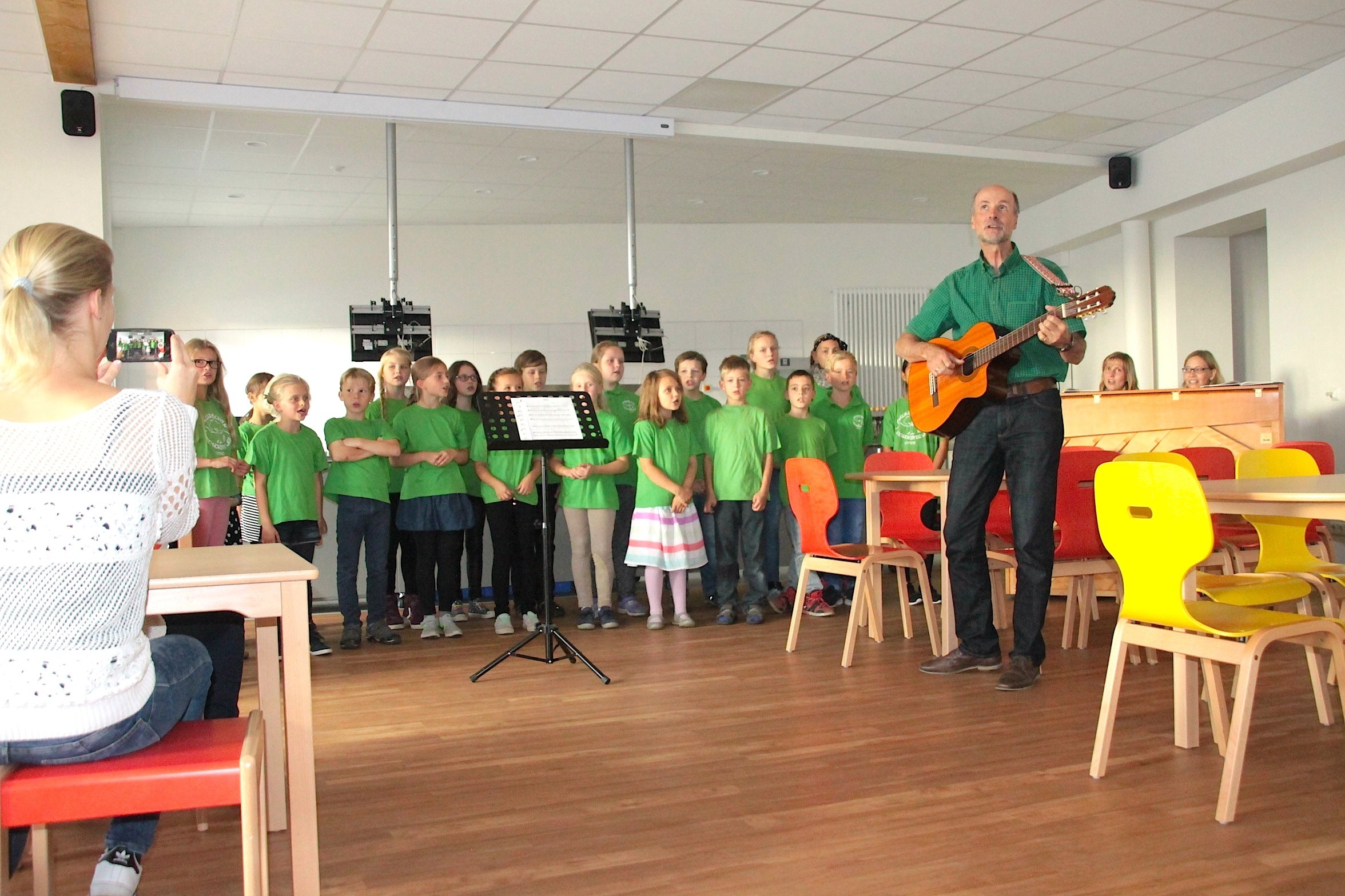 Festlicher Gesang in der neuen Mensa: der Schulchor mit Schulleiter Matthias Großer an der Gitarre