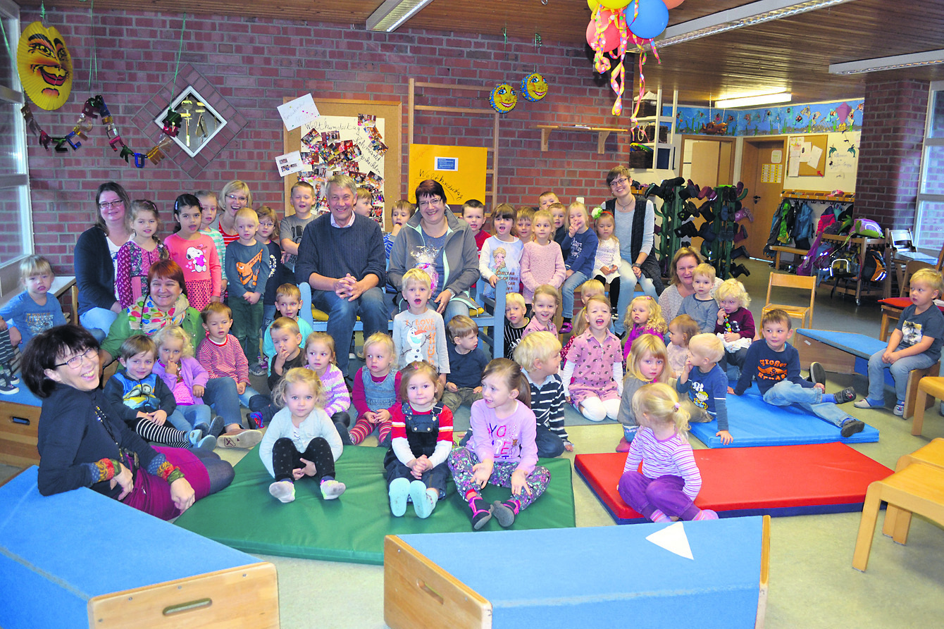 Peter Johannsen und Antje Müller auf der blauen Bank inmitten der Krippen- und Kindergartenkinder