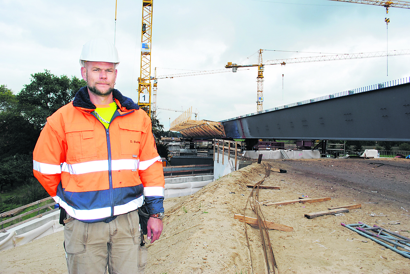 Projektleiter Dennis Babig (Zwickauer Sonderstahlbau) vor dem riesigen, stählernen Haupttragwerk, das Stück für Stück über die Este geschoben wird
