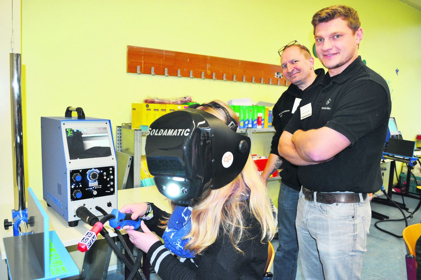 Schülerin Lena beim virtuellen Schweißen mit Jens Gohr (Mi.) und Johann Becker von Mercedes Benz