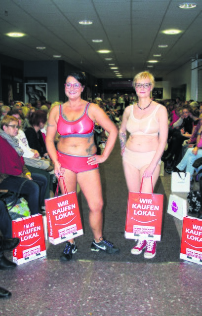 Shoppingsspaß in Sportwäsche: Esther und Steffi präsentieren Bademode und tragen dabei die WOCHENBLATT-Atkionstüten "Wir kaufen lokal"