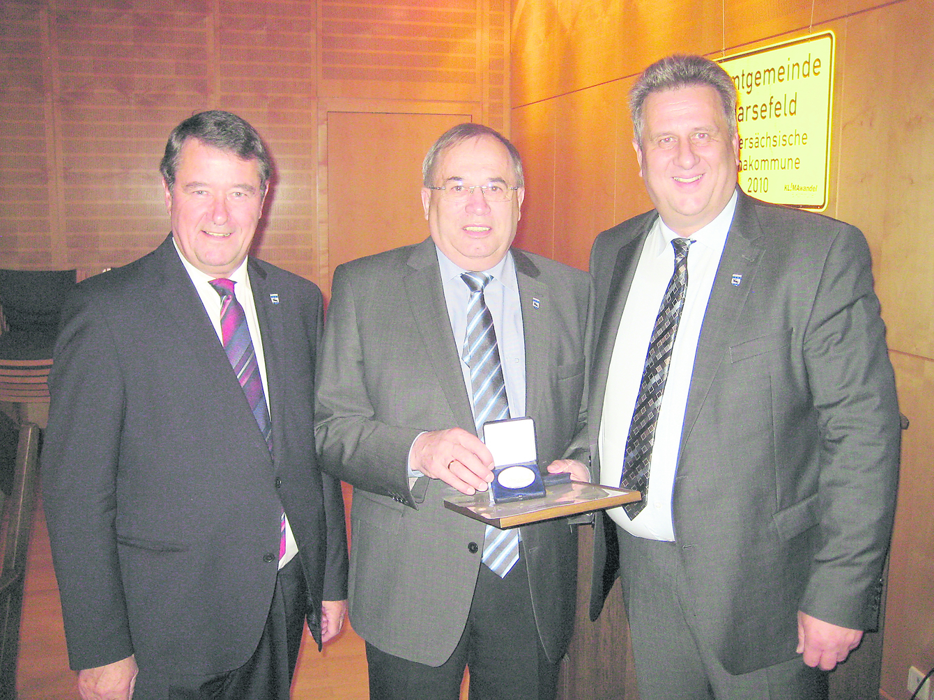 Gemeindedirektor Rainer Schlichtmann (li.) und Bürgermeister Michael Ospalski (re.) überreichen Friedrich Dammann die Medaille