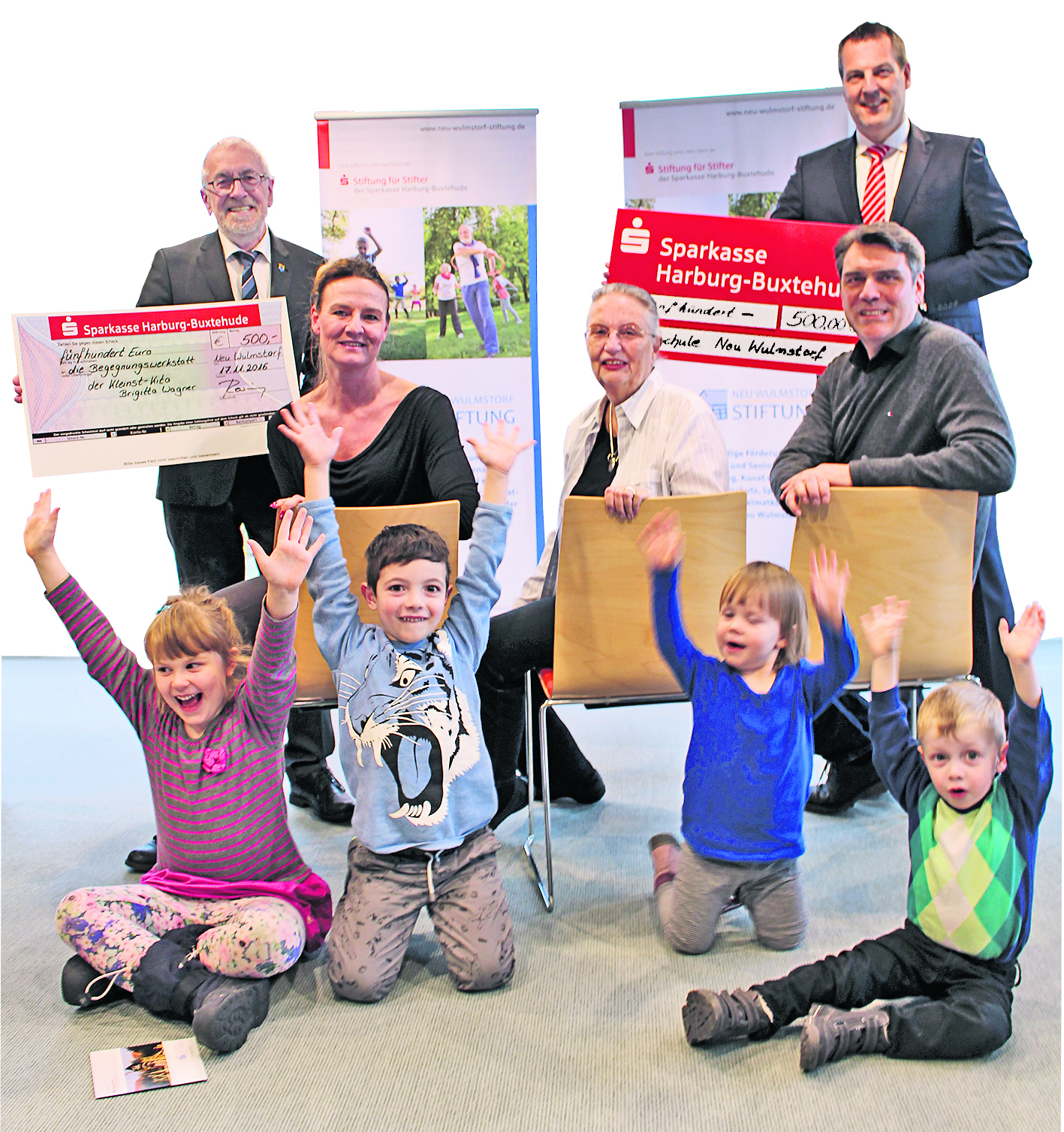 Zwei Schecks über je 500 Euro und glückliche Gewinner: Bürgermeister Rosenzweig (li.) mit Brigitta Wagner, Andreas Sommer (re. hinten) mit Heiko Lépel und der stellvertretenden Stiftungsvorsitzenden Anneliese Scheppelmann (Mitte) sowie Kindern der Kleinst-Kita