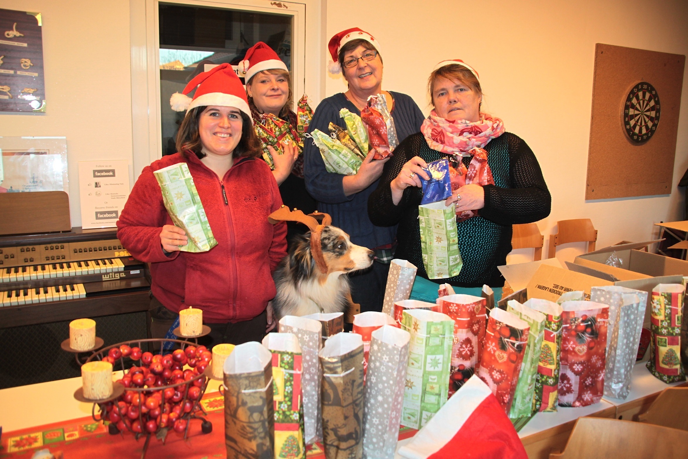 Seemanns-Diakonin Kerstin Schefe (v. li.) und die Ehrenamtlichen Daniela Berliner, Anke Paulini sowie Heike Mundhenke packen Geschenke. Hündin Nala schaut neugierig zu