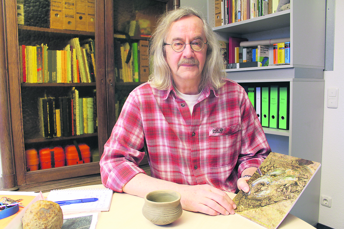 Archäologe Dr. Bernd Habermann hat die ersten Grabungsergebnisse in Immenbeck in einer Schrift zusammengefasst. Ebenfalls zu sehen: ein Tongefäß, Nachbildung einer 1.500 Jahre alten Grabbeigabe