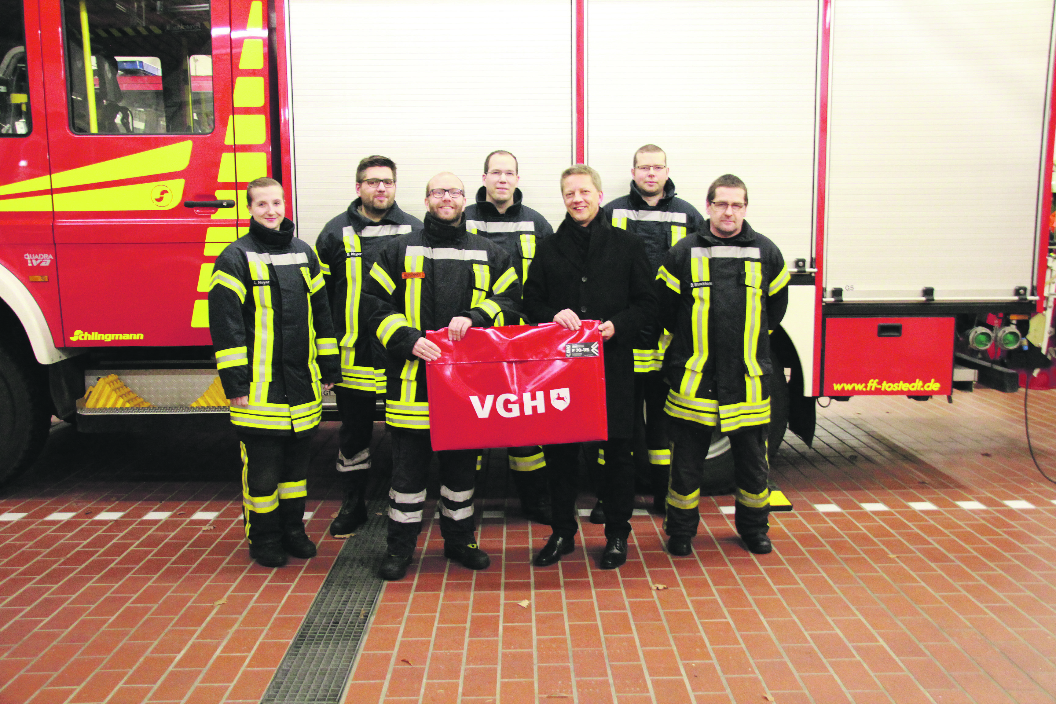 Rüdiger Meier (3. v. re.) überreichte Tostedts Ortsbrandmeister Lars Kretschmer (3. v. li.) den Rauchvorhang