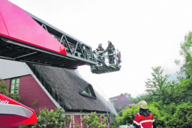 Drehleiter im Einsatz. Feuerwehrleute schützten das reetgedeckte Wohnhaus
