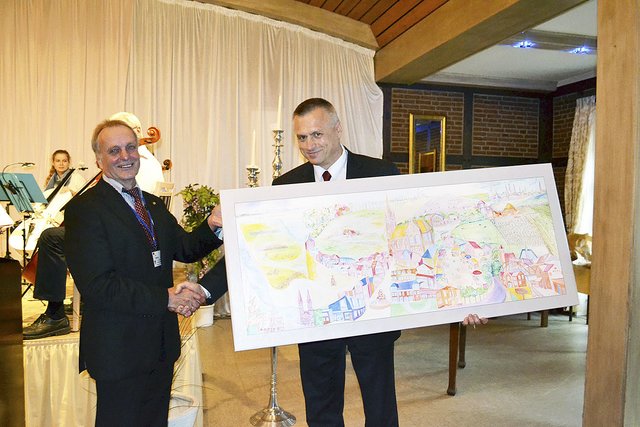 Gerhard Netzel (li.) überreichte Lubaczows Bürgermeister Krzysztof Szpyt eine kleine Version des Gemäldes von Künstler Ingo Thalmann, dessen Original im Rathaus hängt