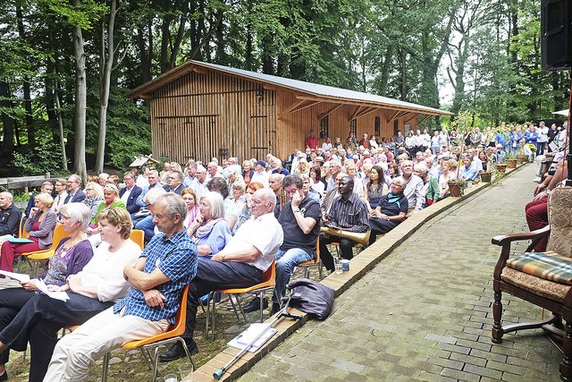 Dicht gedrängt sitzen die Besucher bei der stimmungsvollen Feier auf dem Mühlenhof. Im Hintergrund zu sehen ist die Sägerei