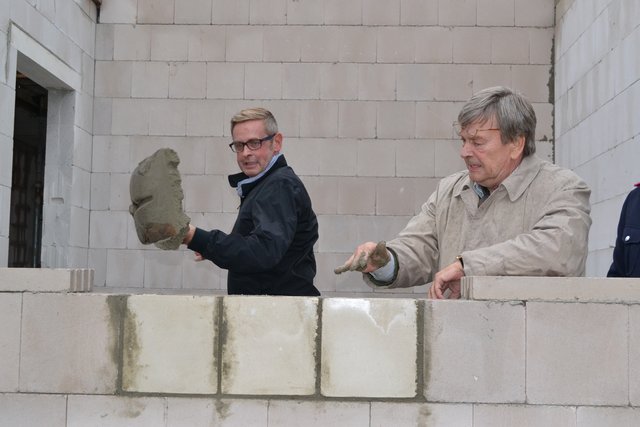 Weil die Kellen fehlten, griff Samtgemeinde-Bürgermeister Heiner Albers kurzerhand zur Schaufel, um den Grundstein zuzumauern. Architekt Claus Juraschek übernahm das Glattstreichen von Hand