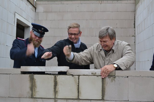 Ortsbrandmeister Arne Gewert (v. li.), Samtgemeinde-Bürgermeister Heiner Albers und Architekt Claus Juraschek klopften noch die Abdecksteine fest