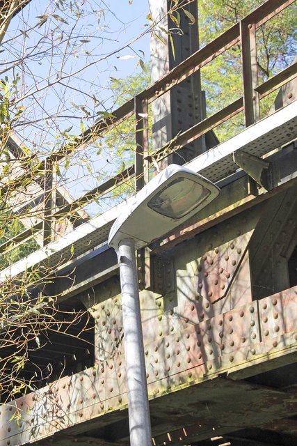 Die Straßenlaterne wird zum Teil von der Brücke und Ästen verdeckt
