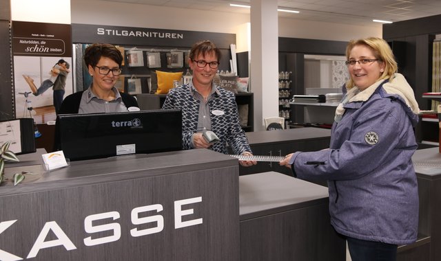 Daniela Lassen (re.) aus Hollern-Twielenfleth möchte das Wohnzimmer renovieren. Sie kauft bei Janine-Christine Lehmann (Mi.) und Birgit Winter von der Firma Scholz ein paar Schienen, damit die Ecken schön gerade ausfallen.