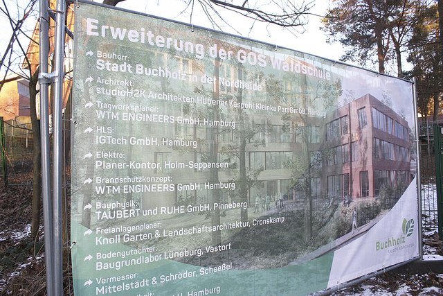 Der Altbau der Waldschule scheint durch das Bauschild