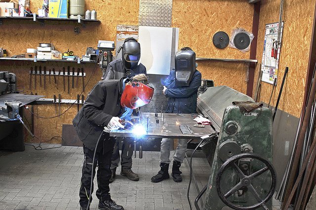 Im Winsener Metallbaubetrieb von Jan Jürgens: Bennet schweißt Metallteile zusammen, 
Lennart (hinten li.) und Jack gucken ihm dabei