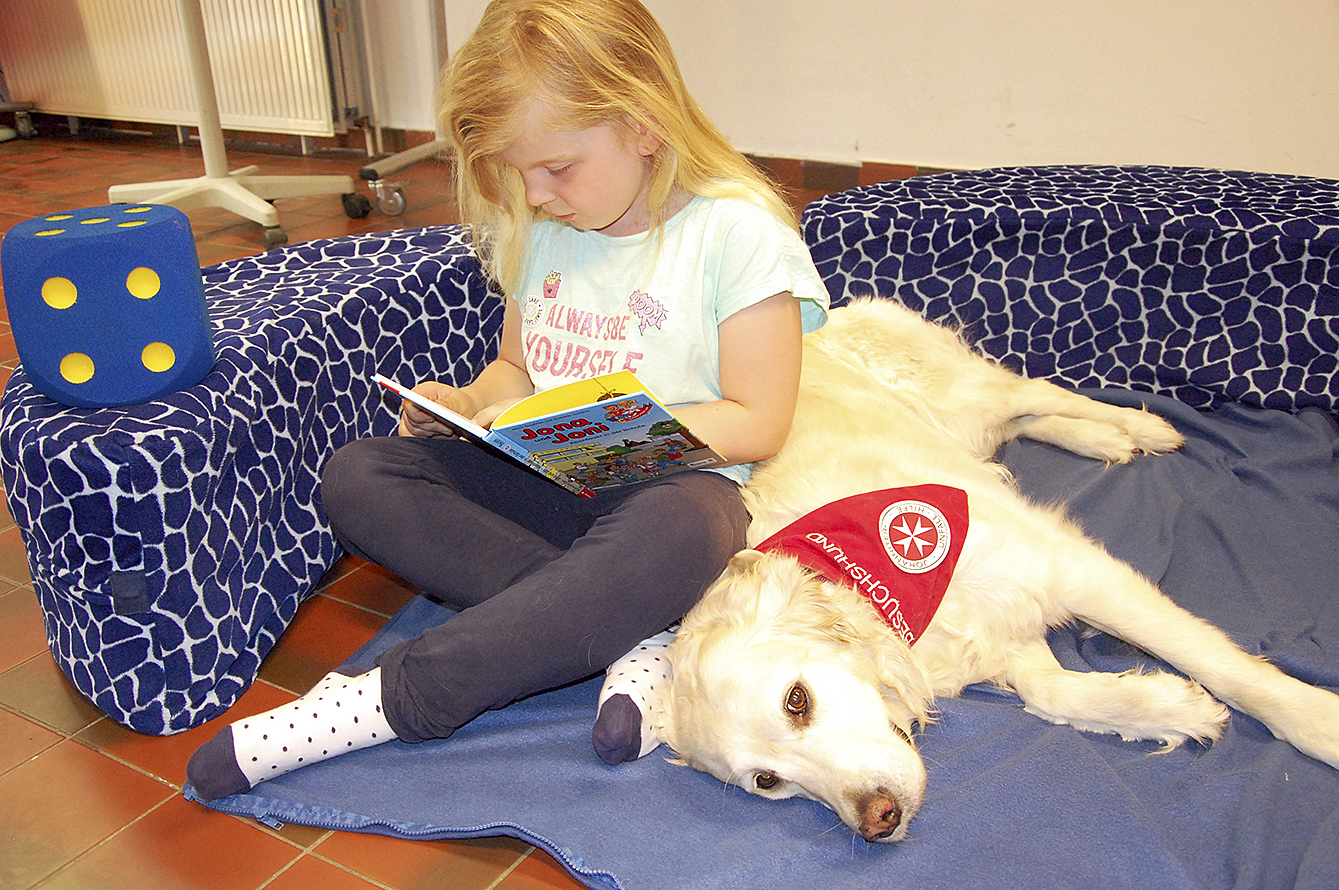 Entspannte Atmosphäre: Johanna liest vor, Johanniter-Bücherhund Emma hört zu
