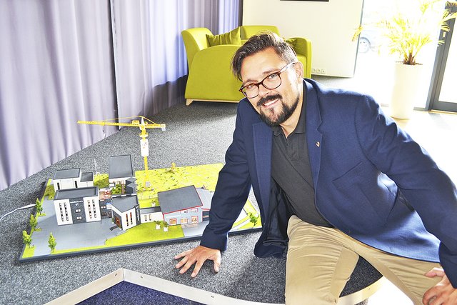 Klaas Dittmer neben einem Modell des Druckstudios und des jetzigen Medienhauses mit dem geplanten Erweiterungsbau (unter dem Kran), in dem 25 Büros entstehen sollen