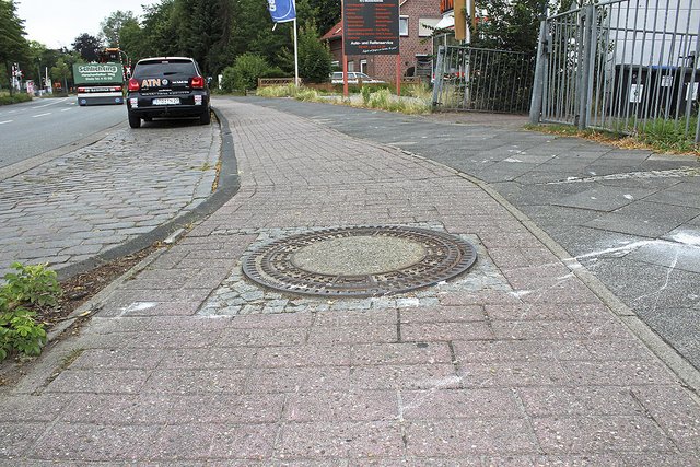 Mehrere Gullideckel ragen gefährlich weit 
aus der Pflasterung heraus