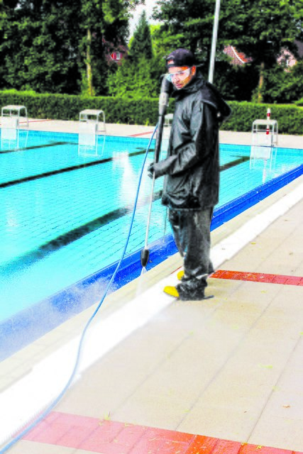 Schwimmmeister-Azubi Mohammad Javad Alamdari befreit Fußwege und Beckenrinnen per Wasserstrahl von Grünbewuchs