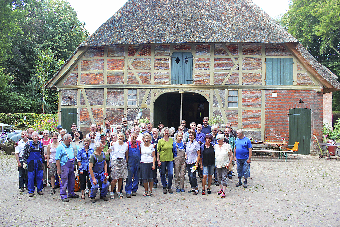 Vereinsmitglieder stehen vor dem Haupthaus des Gebäude-Ensembles der Wassermühle