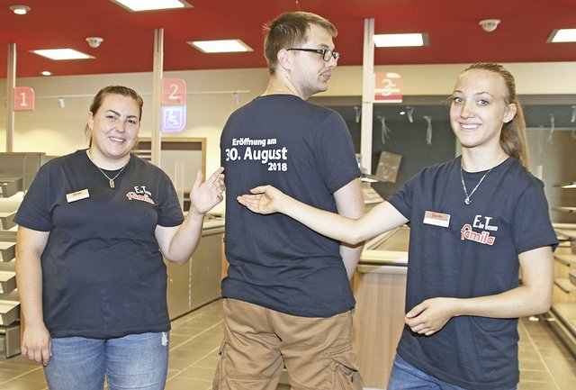Die Auszubildenden Jasmin Rudloff (li.) und Lara Rauch präsentieren den Aufdruck auf dem T-Shirt des stellvertretenden Marktleiters Andreas Blume