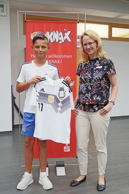 Yvonne Hinck, als Verantwortliche für den Jugendmarkt bei der Sparkasse, überreichte dem glücklichen Luca Werner sein Gewinner-Trikot  Foto: Sparkasse