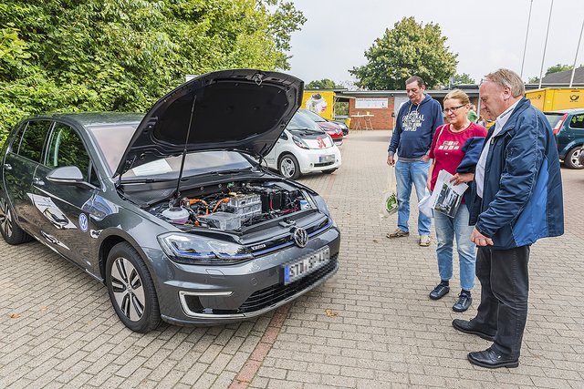 Dirk Mense (re.) vom Autohaus Spreckelsen erklärt den Bürgerbus-Fahrern Karin Tietchen und Dieter Müller die eTechnik im Motorraum des eGolfs